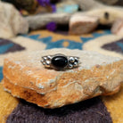 Handcrafted sterling silver Navajo ring featuring a polished oval Black Onyx cabochon in a smooth bezel setting, accented by decorative sterling silver bead clusters on each side of the gemstone.