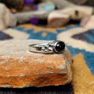 Handcrafted sterling silver Navajo ring featuring a polished oval Black Onyx cabochon in a smooth bezel setting, accented by decorative sterling silver bead clusters on each side of the gemstone; side view.