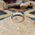 Handcrafted sterling silver Navajo ring featuring a polished oval Black Onyx cabochon in a smooth bezel setting, accented by decorative sterling silver bead clusters on each side of the gemstone; underside view.