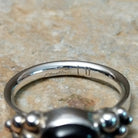 Handcrafted sterling silver Navajo ring featuring a polished oval Black Onyx cabochon in a smooth bezel setting, accented by decorative sterling silver bead clusters on each side of the gemstone; artisan and Sterling Silver stamp.