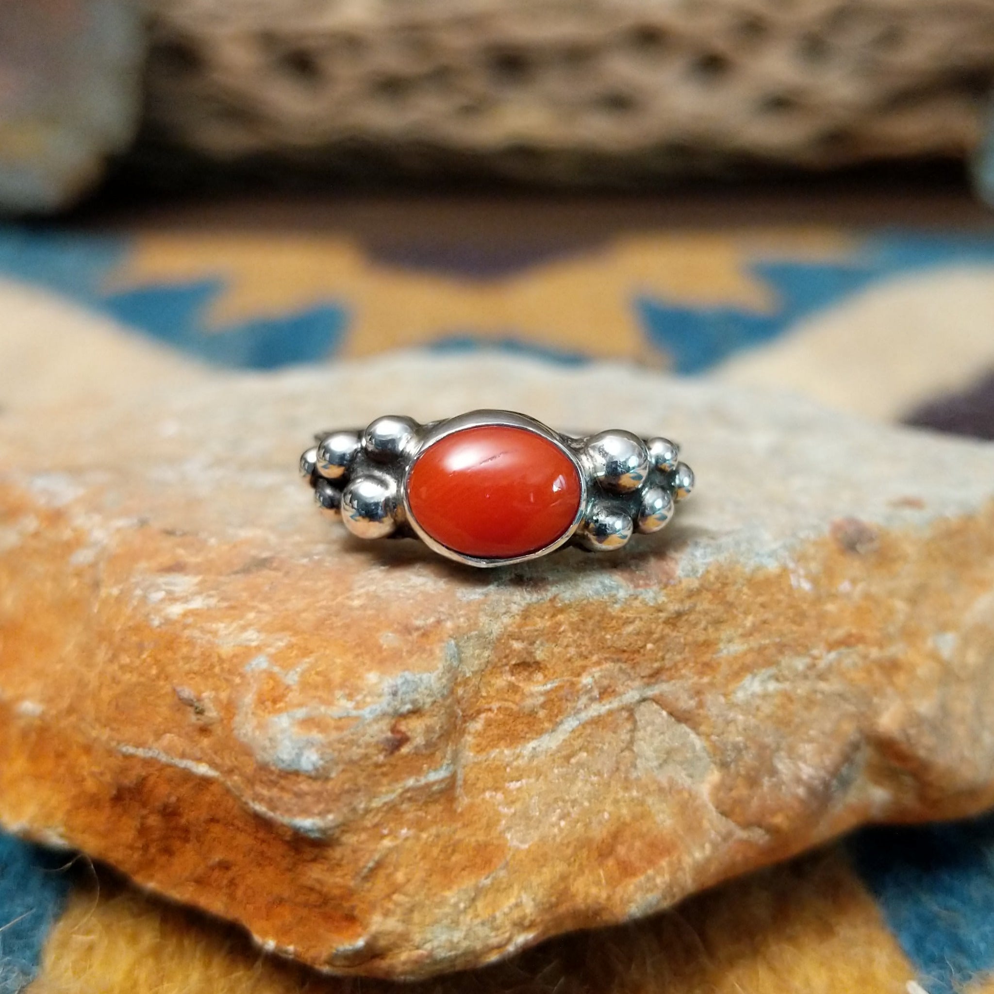 Handcrafted sterling silver dotted coral ring by Lowell Draper, featuring an oval coral cabochon with polished silver bead accents.