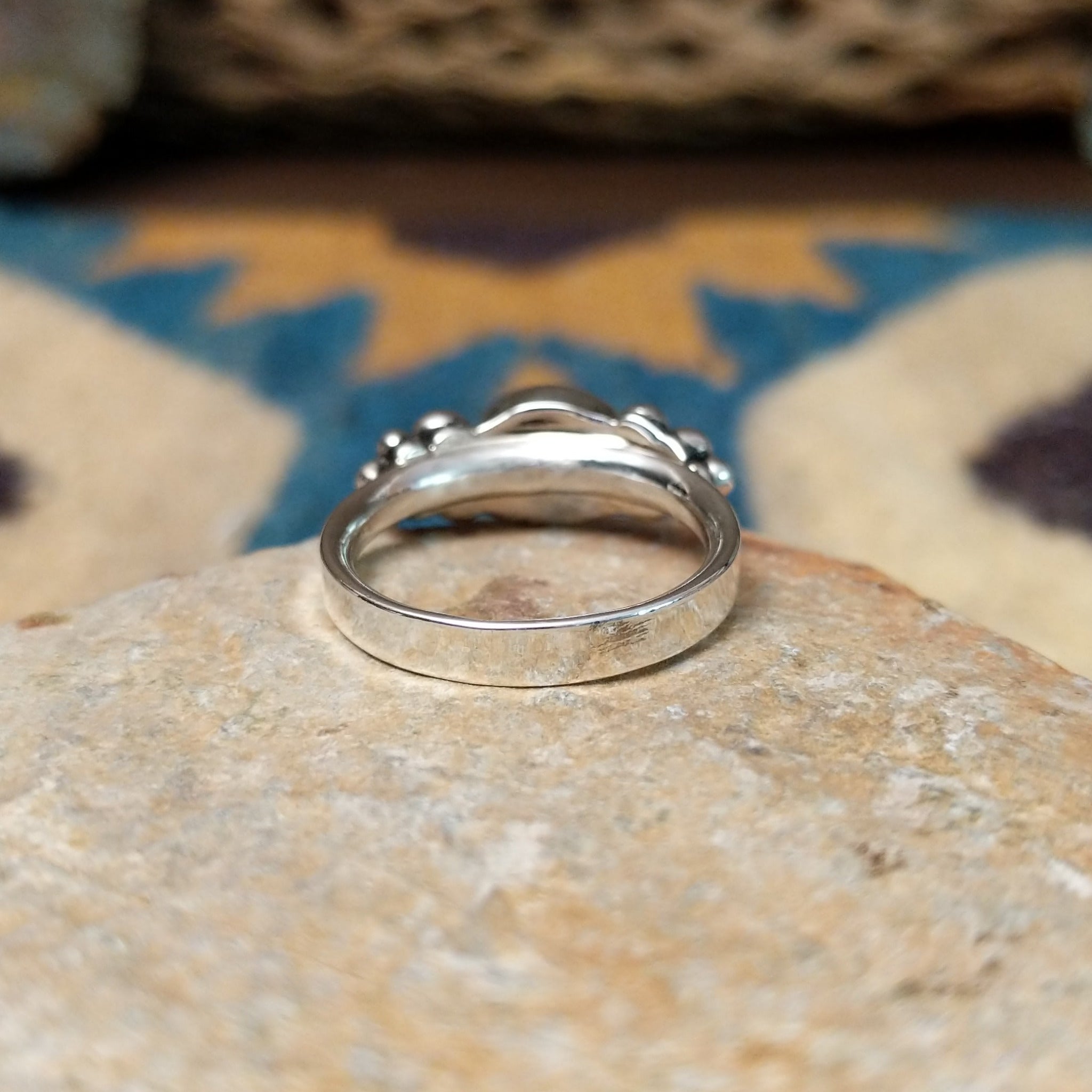 Handcrafted sterling silver dotted coral ring by Lowell Draper, featuring an oval coral cabochon with polished silver bead accents; underside view.