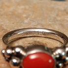 Handcrafted sterling silver dotted coral ring by Lowell Draper, featuring an oval coral cabochon with polished silver bead accents; artisan and Sterling Silver stamp.