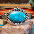 Sterling silver cuff with Kingman turquoise set in a large, oval bezel that is framed by dotted accents, while the band features a unique twist design.