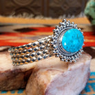 Sterling silver cuff with Kingman turquoise set in a large, oval bezel that is framed by dotted accents, while the band features a unique twist design.