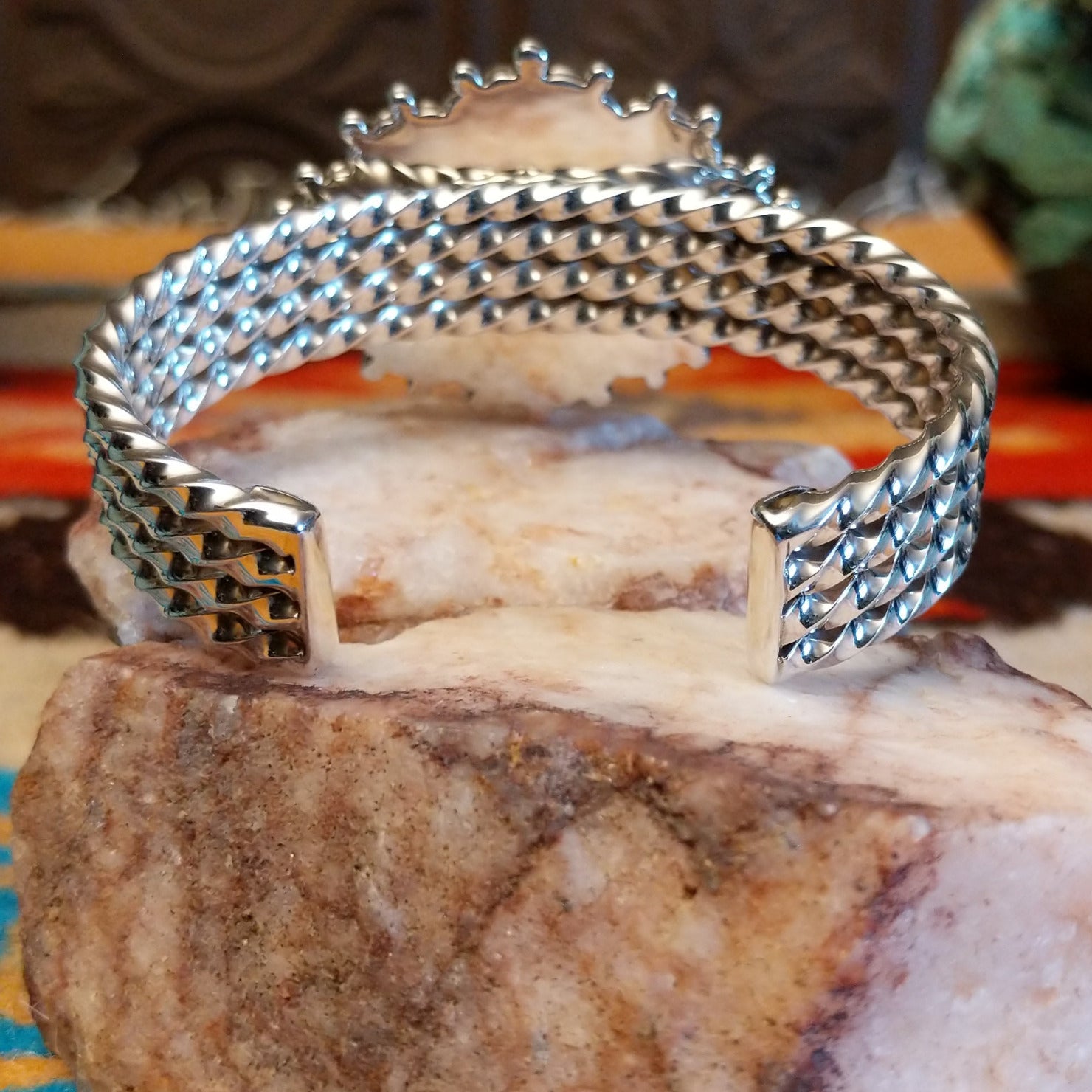 Sterling silver cuff with Kingman turquoise set in a large, oval bezel that is framed by dotted accents, while the band features a unique twist design.