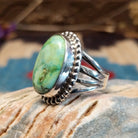Sterling silver ring with Sonoran gold turquoise set in a large, oval bezel that is framed by dotted accents.