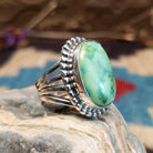 Sterling silver ring with Sonoran gold turquoise set in a large, oval bezel that is framed by dotted accents.