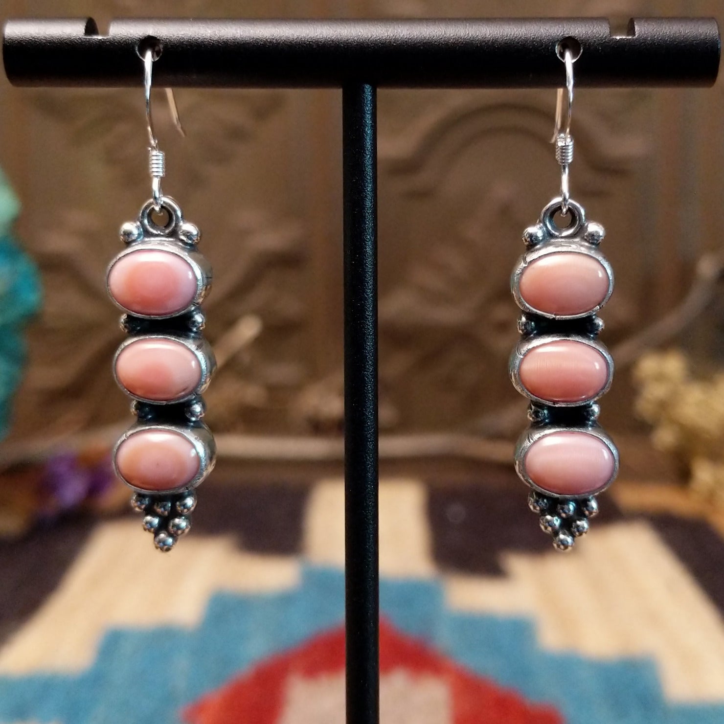 Sterling silver earrings with pink conch shells set in three bezels, framed by dotted accents.