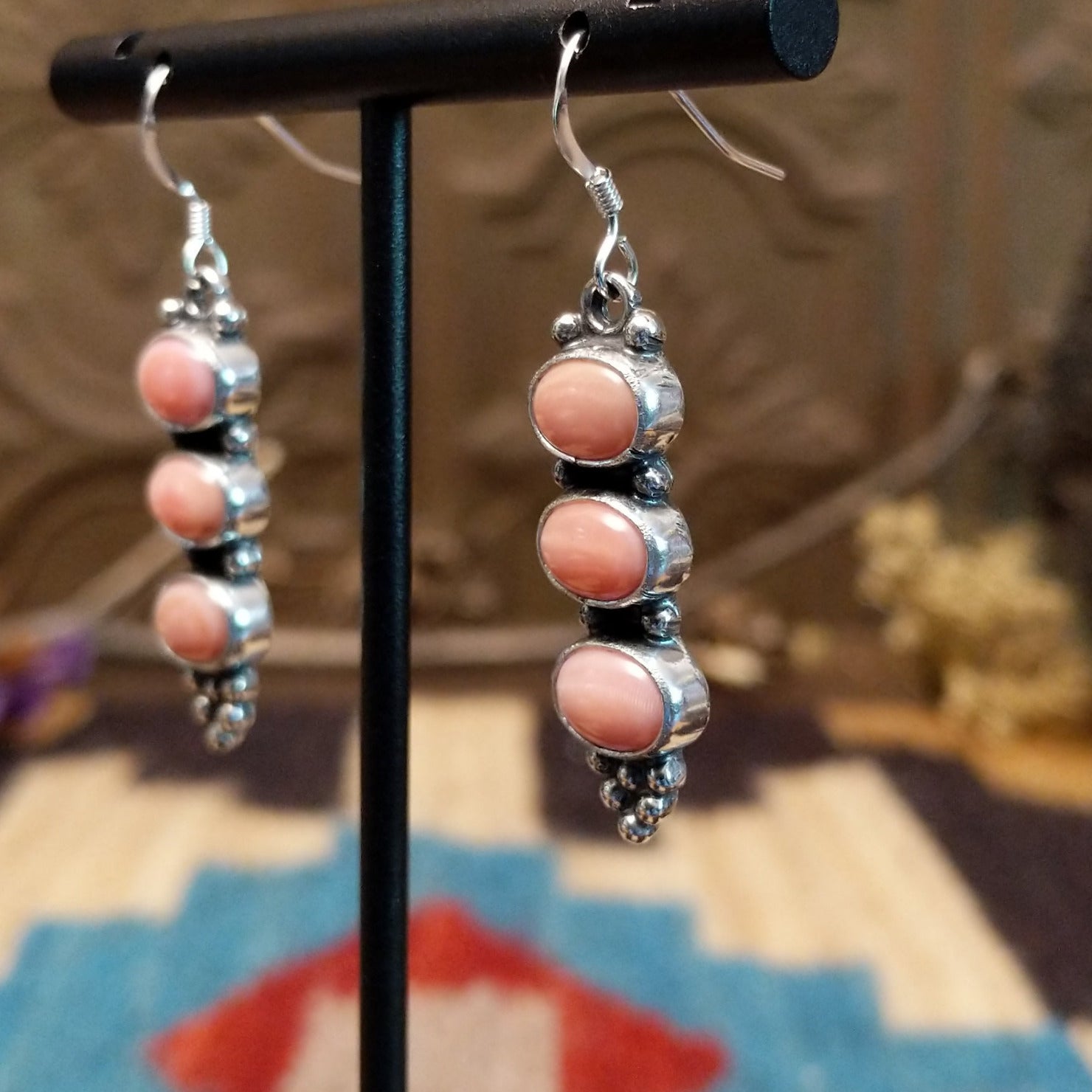 Sterling silver earrings with pink conch shells set in three bezels, framed by dotted accents.