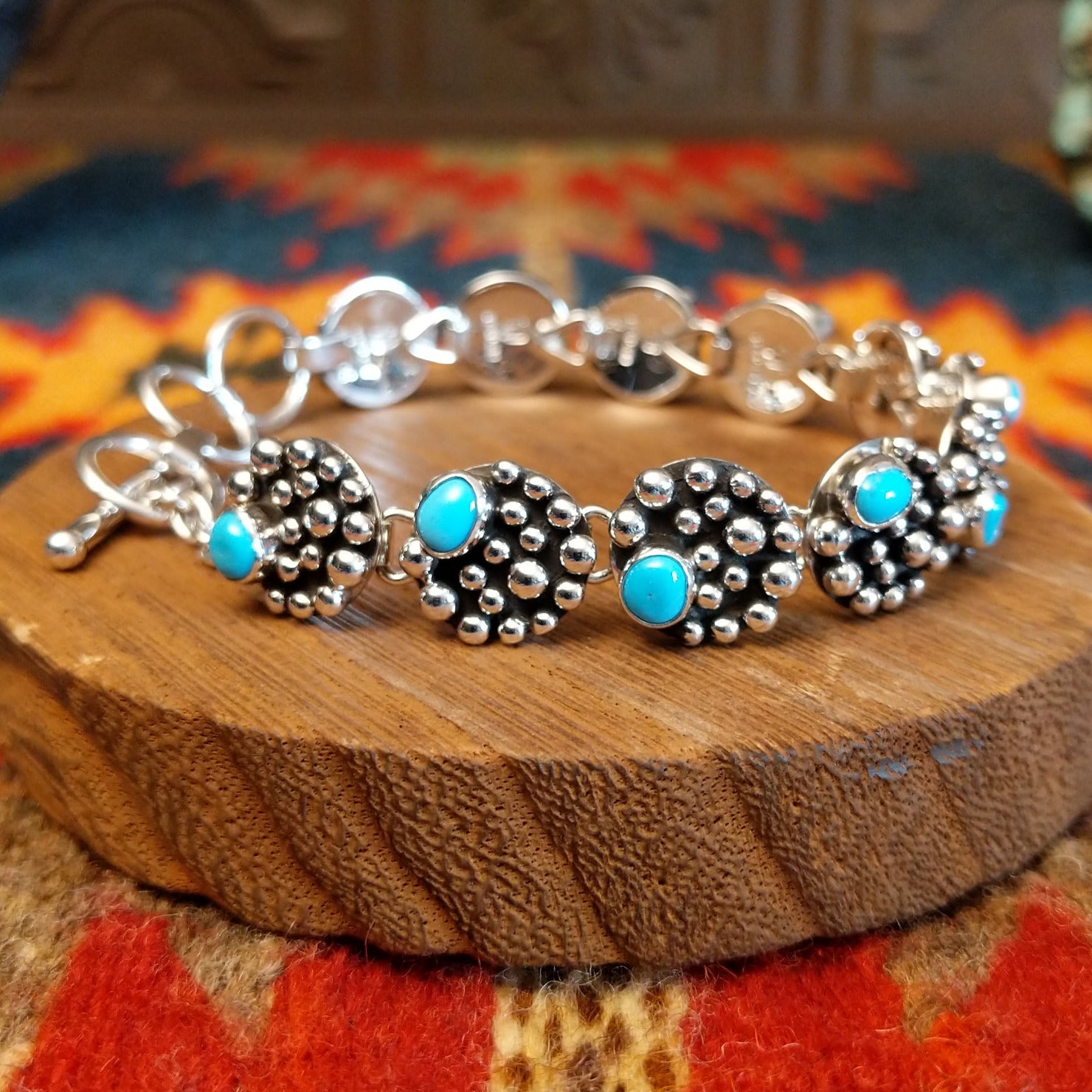 Sterling silver bracelet with dotted settings and turquoise set in small, round bezels.