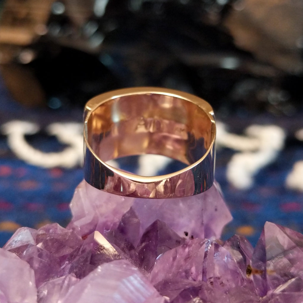 The polished gold, tapered band of the ring.