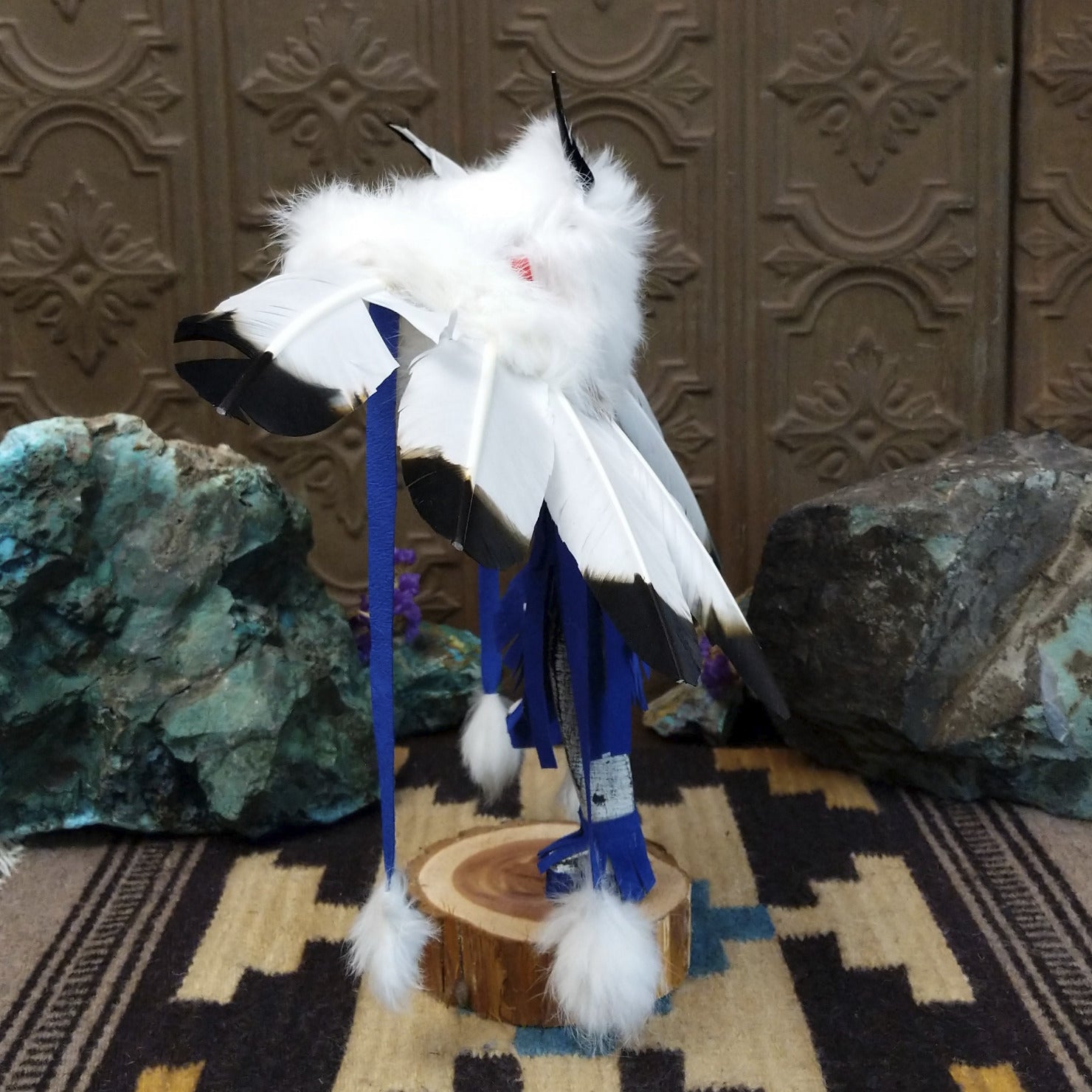 Navajo-made eagle kachina doll by M. C. with outstretched feathered wings, blue mask, yellow beak, and white feather collar.