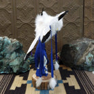 Navajo-made eagle kachina doll by M. C. with outstretched feathered wings, blue mask, yellow beak, and white feather collar.