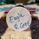 Underside of mini eagle kachina doll showing handwritten signature and label on wood base.