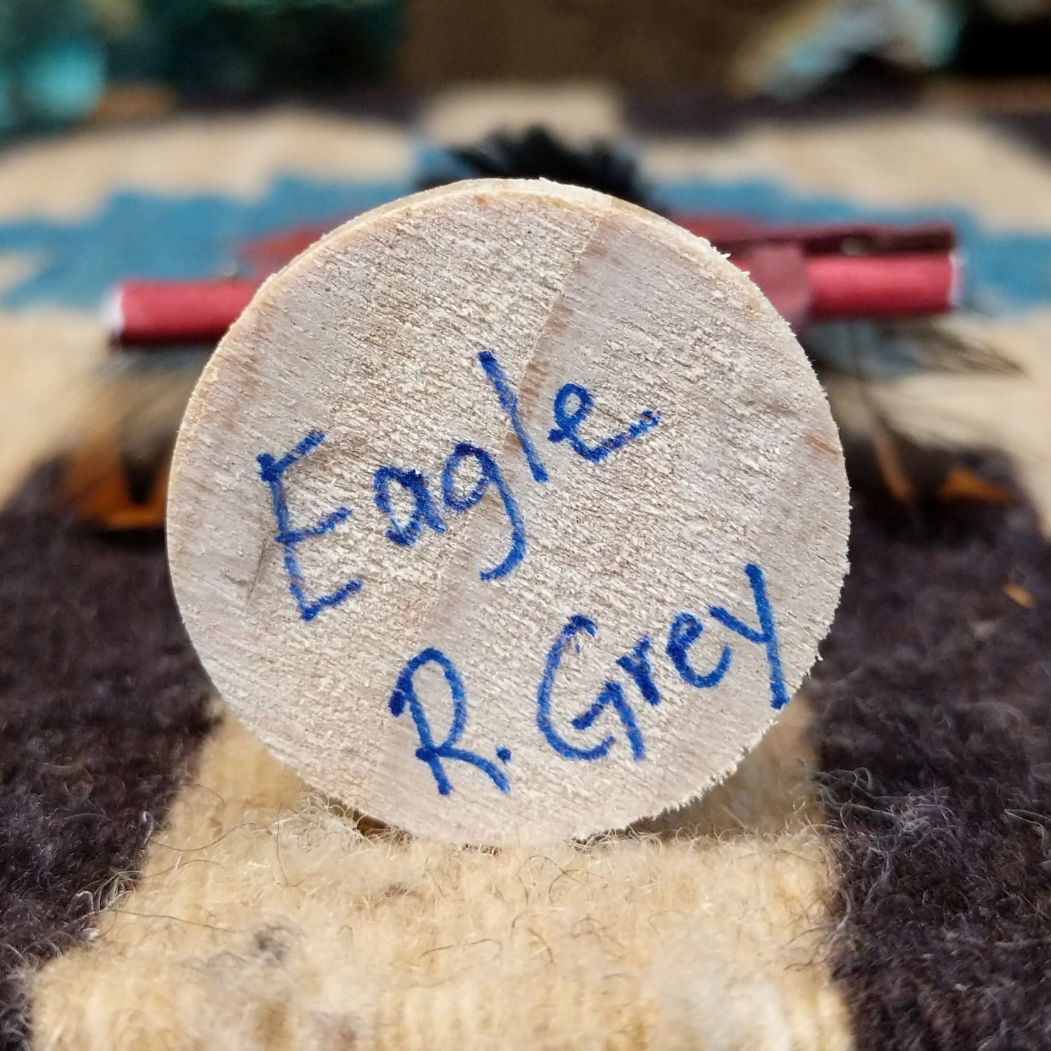Underside of mini eagle kachina doll showing handwritten signature and label on wood base.