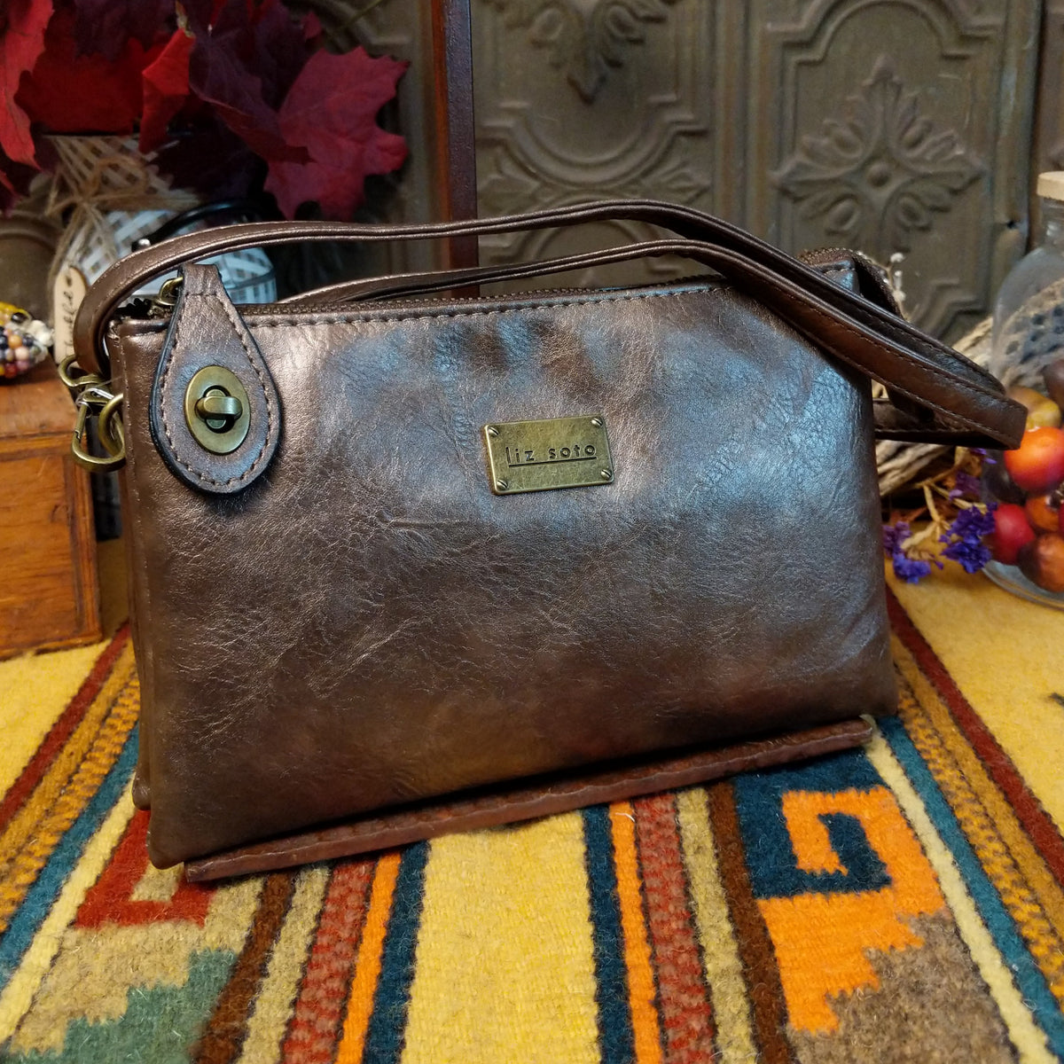 Ella Handbag by Liz Soto featuring a compact structured silhouette, textured exterior, dual handles, turn-lock accent, top zip closure, and rectangular Liz Soto logo plaque.