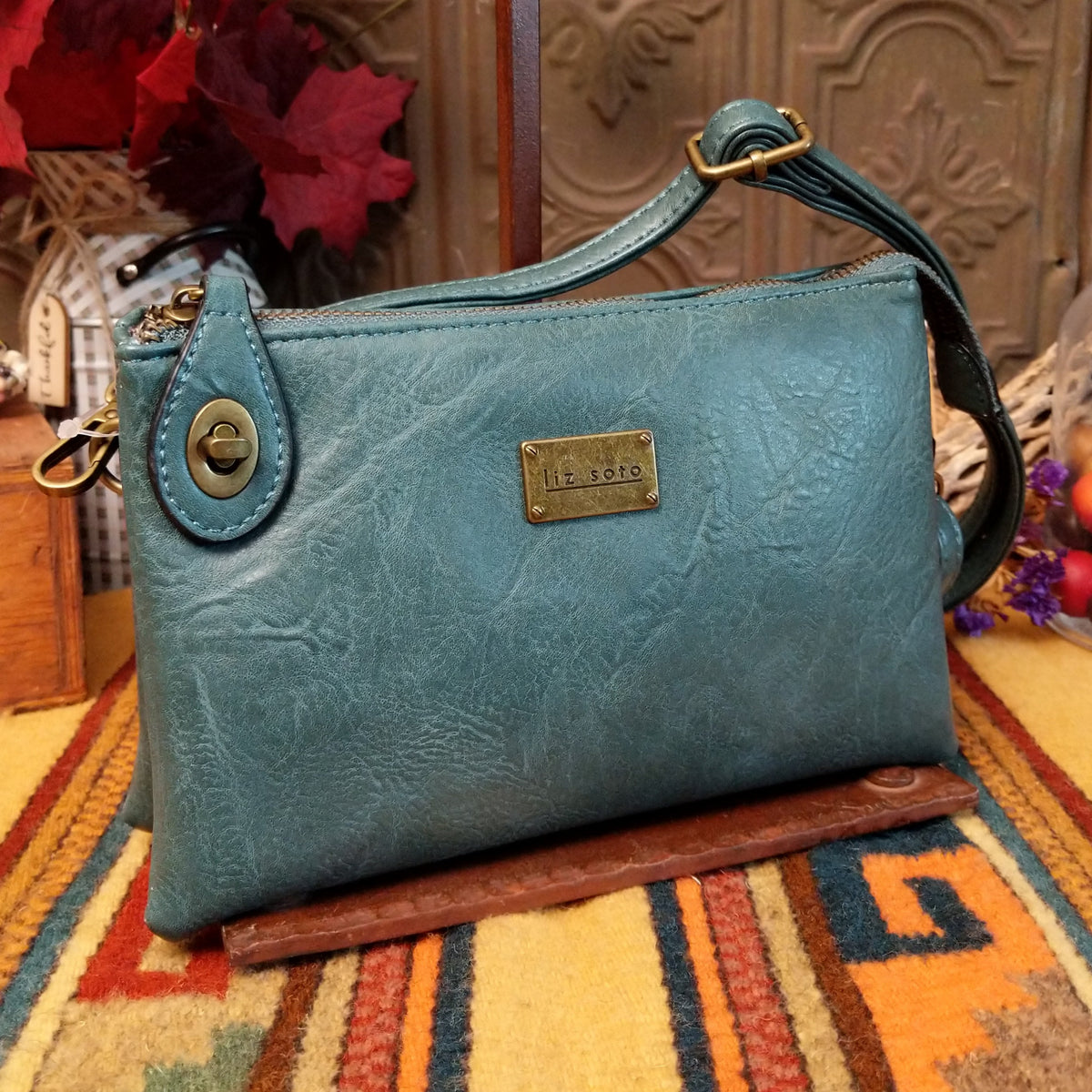 Ella Handbag by Liz Soto featuring a compact structured silhouette, textured exterior, dual handles, turn-lock accent, top zip closure, and rectangular Liz Soto logo plaque.