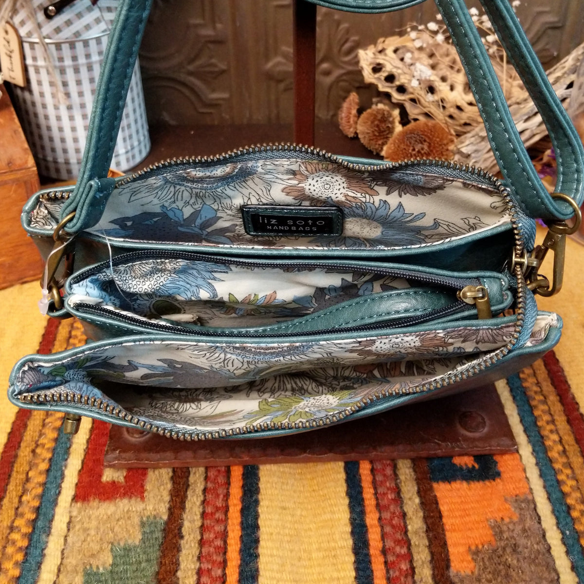Ella Handbag by Liz Soto featuring a compact structured silhouette, textured exterior, dual handles, turn-lock accent, top zip closure, and rectangular Liz Soto logo plaque; interior view.
