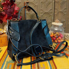 Emma Crossbody Bag by Liz Soto featuring a structured silhouette, mixed-texture panels, top handle, zippered compartment, decorative zipper pulls, and layered leaf-shaped charms; back view.