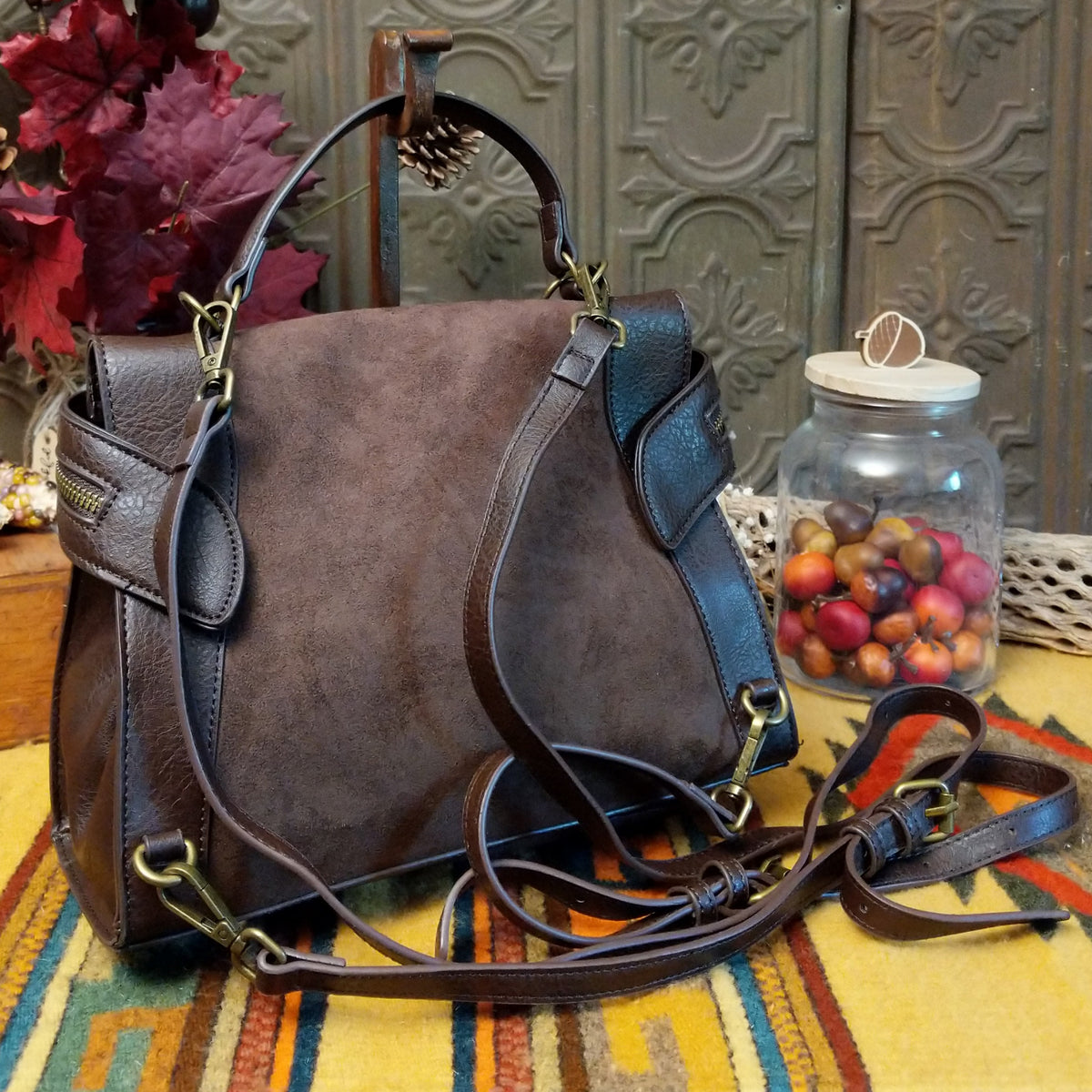 Emma Crossbody Bag by Liz Soto featuring a structured silhouette, mixed-texture panels, top handle, zippered compartment, decorative zipper pulls, and layered leaf-shaped charms; back view.