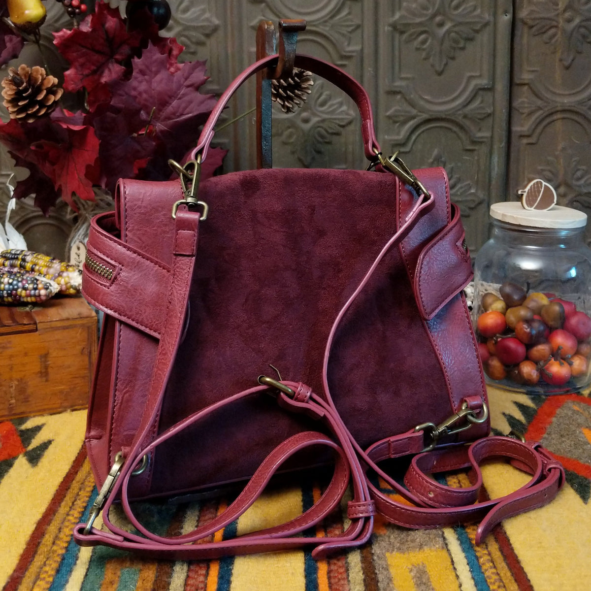 Emma Crossbody Bag by Liz Soto featuring a structured silhouette, mixed-texture panels, top handle, zippered compartment, decorative zipper pulls, and layered leaf-shaped charms; back view.