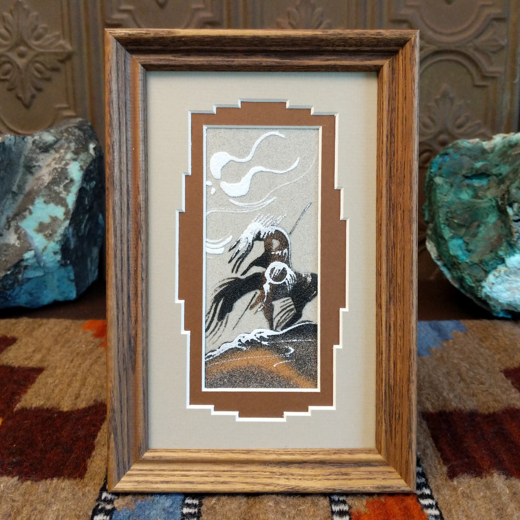 Gray tones of sand creating a storytelling piece about the end of a trail with pops of browns set within a wooden frame.