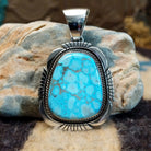 Sterling silver pendant with turquoise set in a large bezel, framed by twisted rope and etched designs.