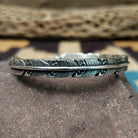 Etched silver feather cuff by Raymond Coriz, featuring a handcrafted sterling silver feather design with intricate engraved details and traditional Southwestern-inspired craftsmanship.