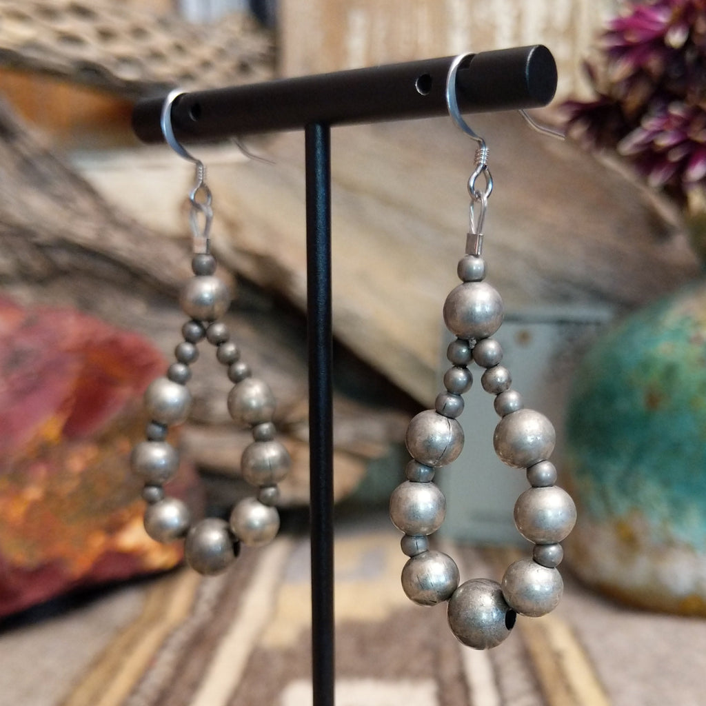 A pair of silver earrings, featuring a cascade of polished spherical beads.