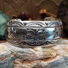 Wide sterling silver cuff bracelet with a raised leaf motif, hand-stamped details, and oxidized accents.