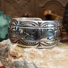 Wide sterling silver cuff bracelet with a raised leaf motif, hand-stamped details, and oxidized accents.