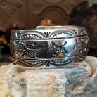 Wide sterling silver cuff bracelet with a raised leaf motif, hand-stamped details, and oxidized accents.