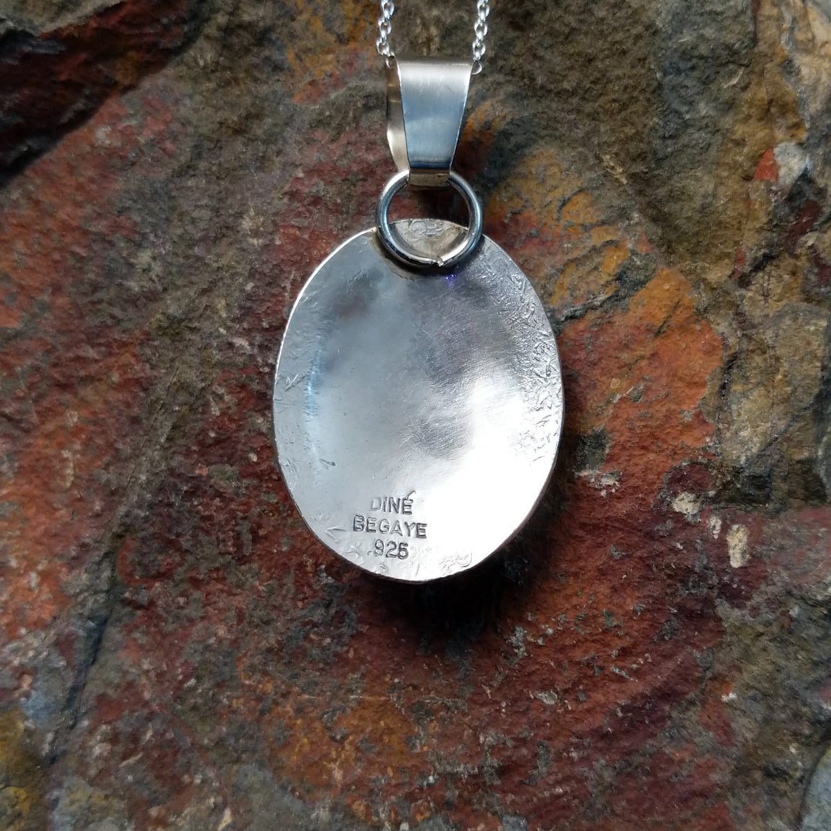 Turquoise pendant by Harrison and Betty Begaye featuring three oval turquoise stones surrounded by detailed sterling silver feathers, twisted rope, stamped borders, and silver accents; artisan and .925 (Sterling Silver) stamp.