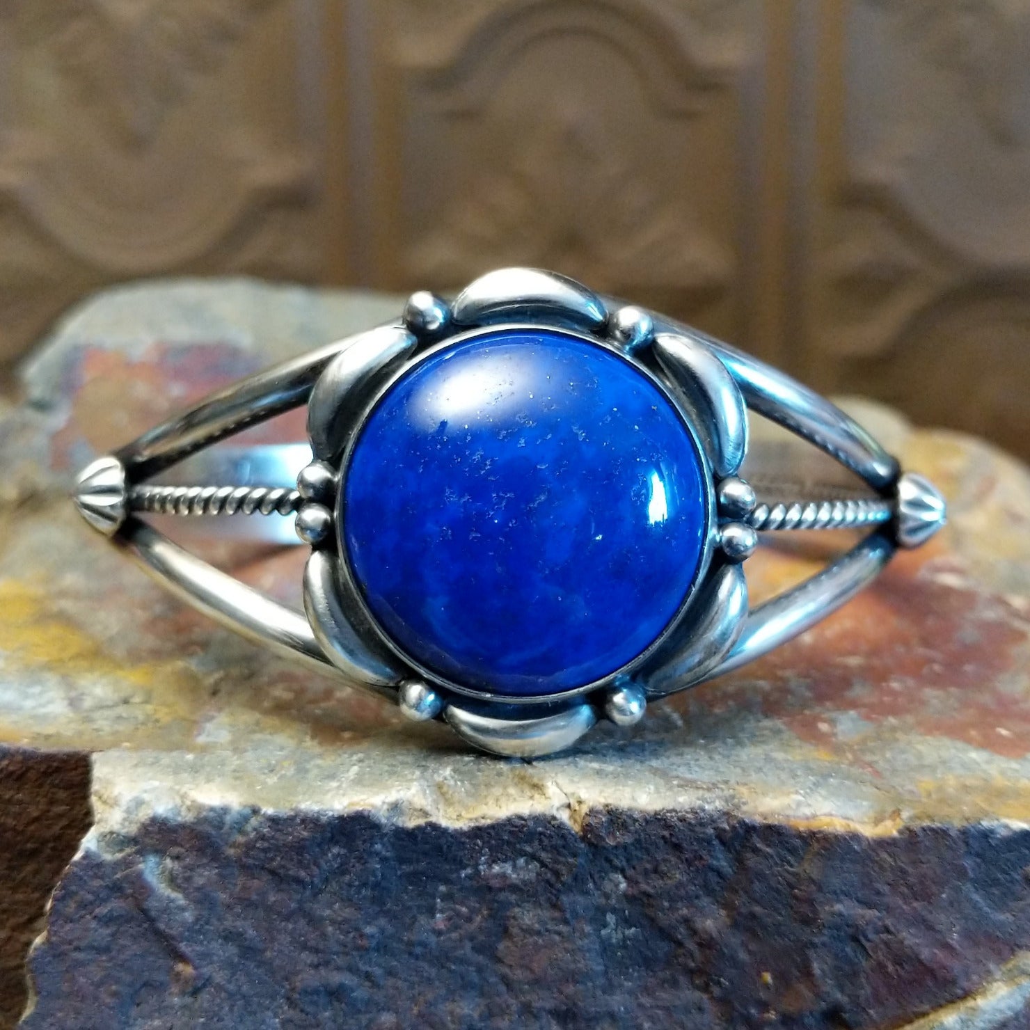 Sterling silver cuff with lapis set in the round bezel and floral silverwork along the band.