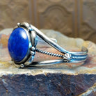 Sterling silver cuff with lapis set in the round bezel and floral silverwork along the band.