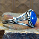 Sterling silver cuff with lapis set in the round bezel and floral silverwork along the band.