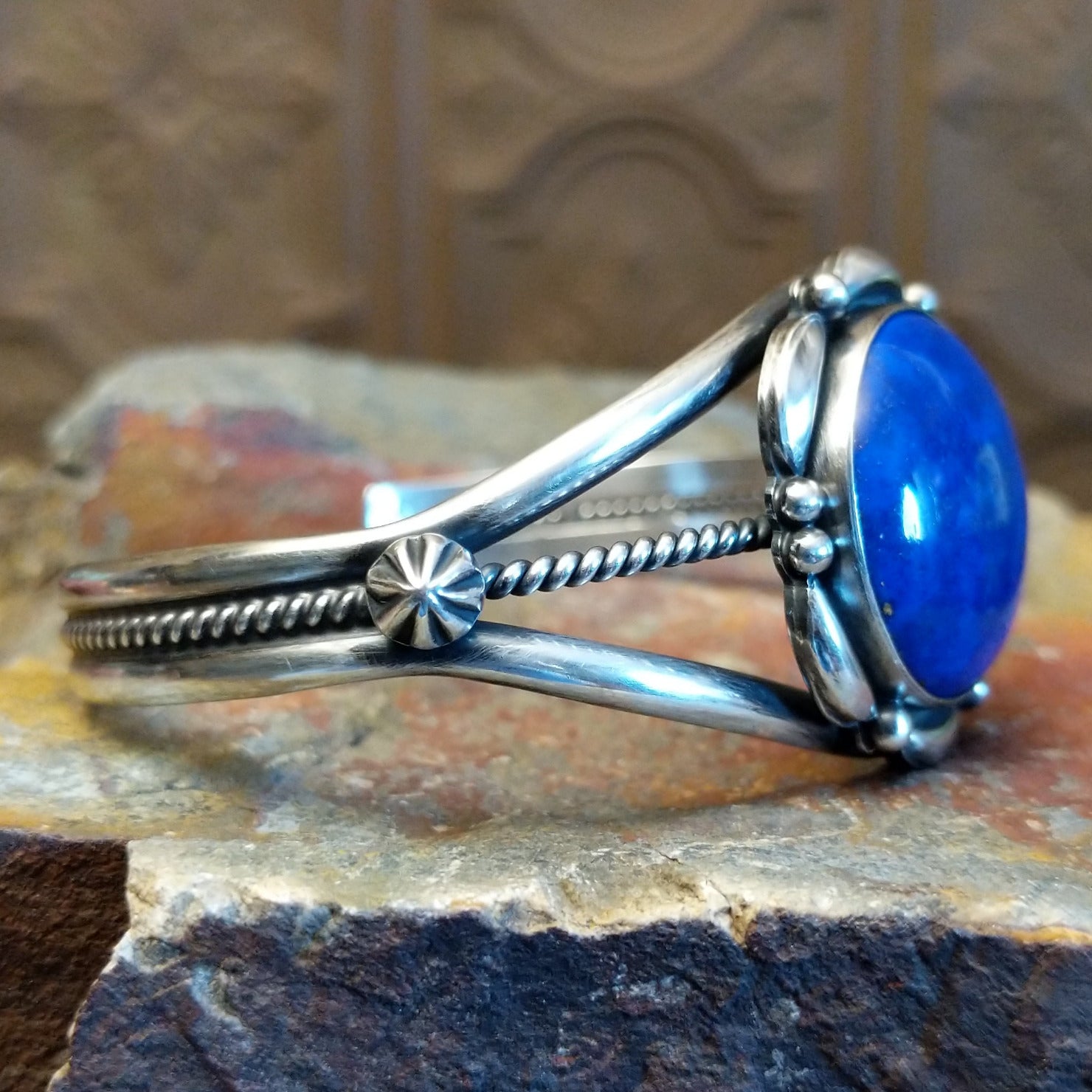 Sterling silver cuff with lapis set in the round bezel and floral silverwork along the band.
