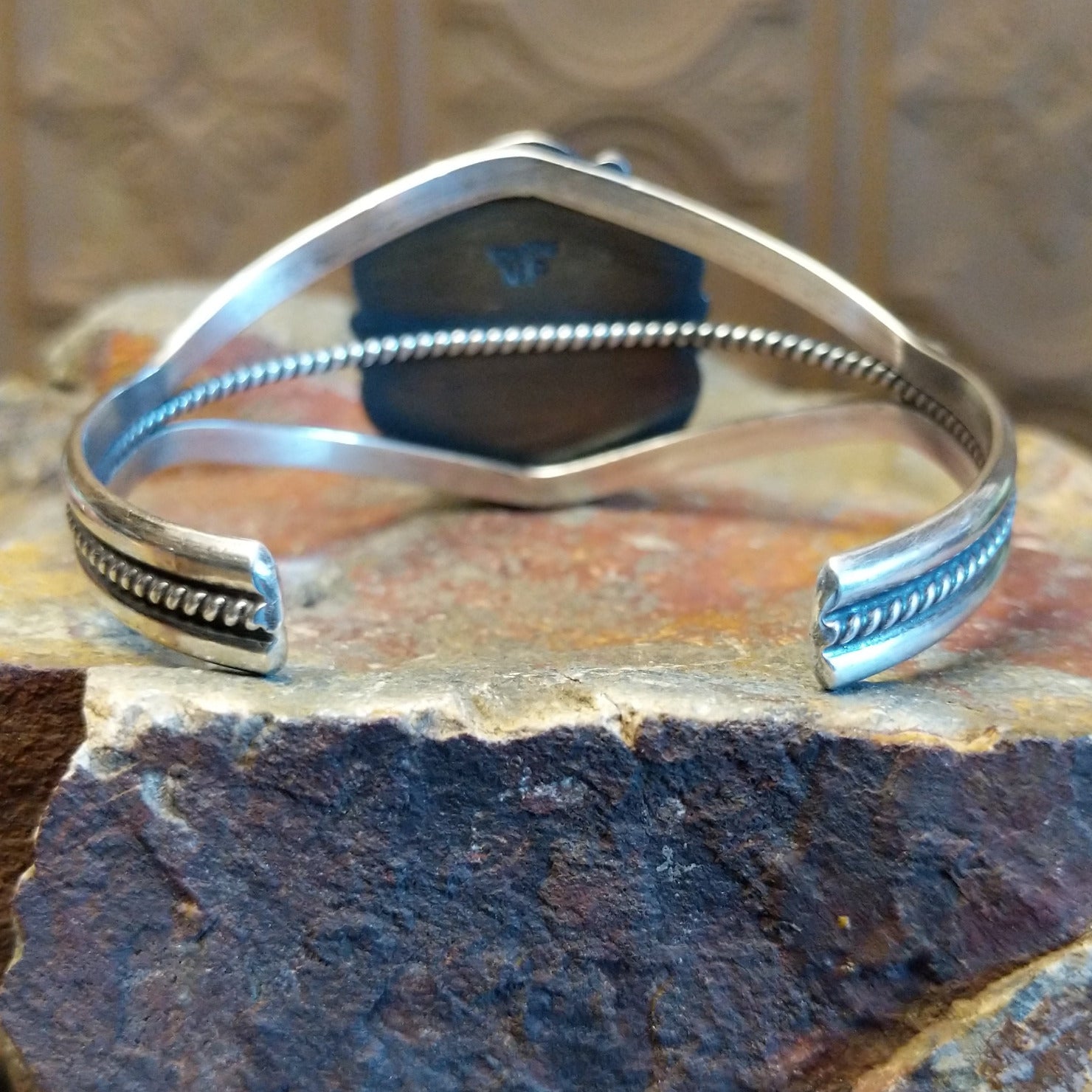 Sterling silver cuff with lapis set in the round bezel and floral silverwork along the band.