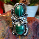 Sterling silver ring with two malachite stones set in the bezels framed by twisted rope and floral accents.