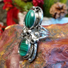 Sterling silver ring with two malachite stones set in the bezels framed by twisted rope and floral accents.