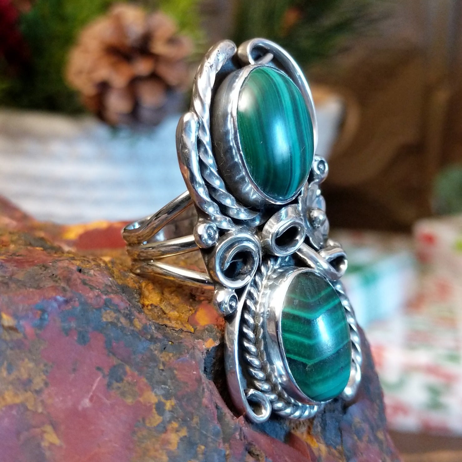Sterling silver ring with two malachite stones set in the bezels framed by twisted rope and floral accents.