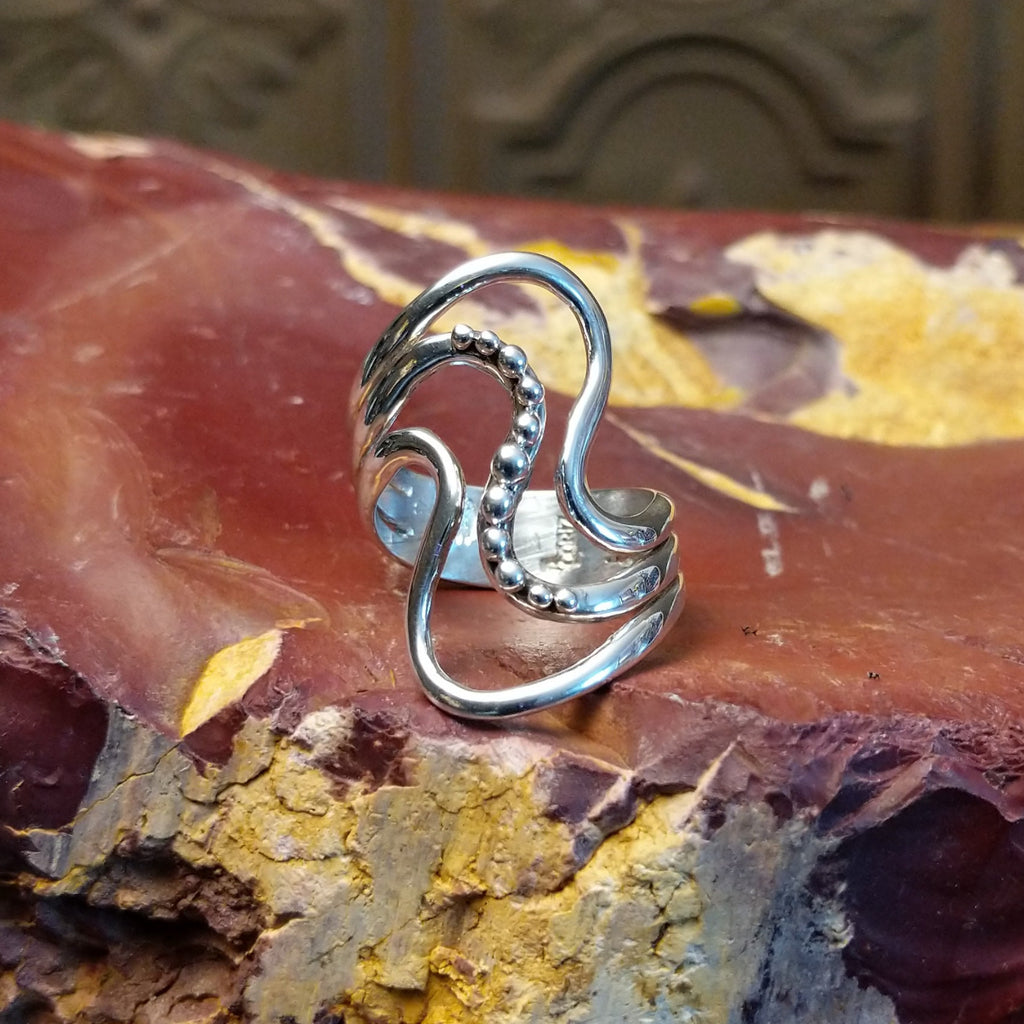 Sterling silver ring with a layered, flowing effect and dot work.
