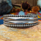 Wide silver cuff by Marc Antia with polished bands, twisted wire detail, and fluted silver borders.