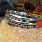 Wide silver cuff by Marc Antia with polished bands, twisted wire detail, and fluted silver borders.