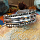 Wide silver cuff by Marc Antia with polished bands, twisted wire detail, and fluted silver borders.