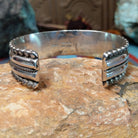 Wide silver cuff by Marc Antia with polished bands, twisted wire detail, and fluted silver borders.