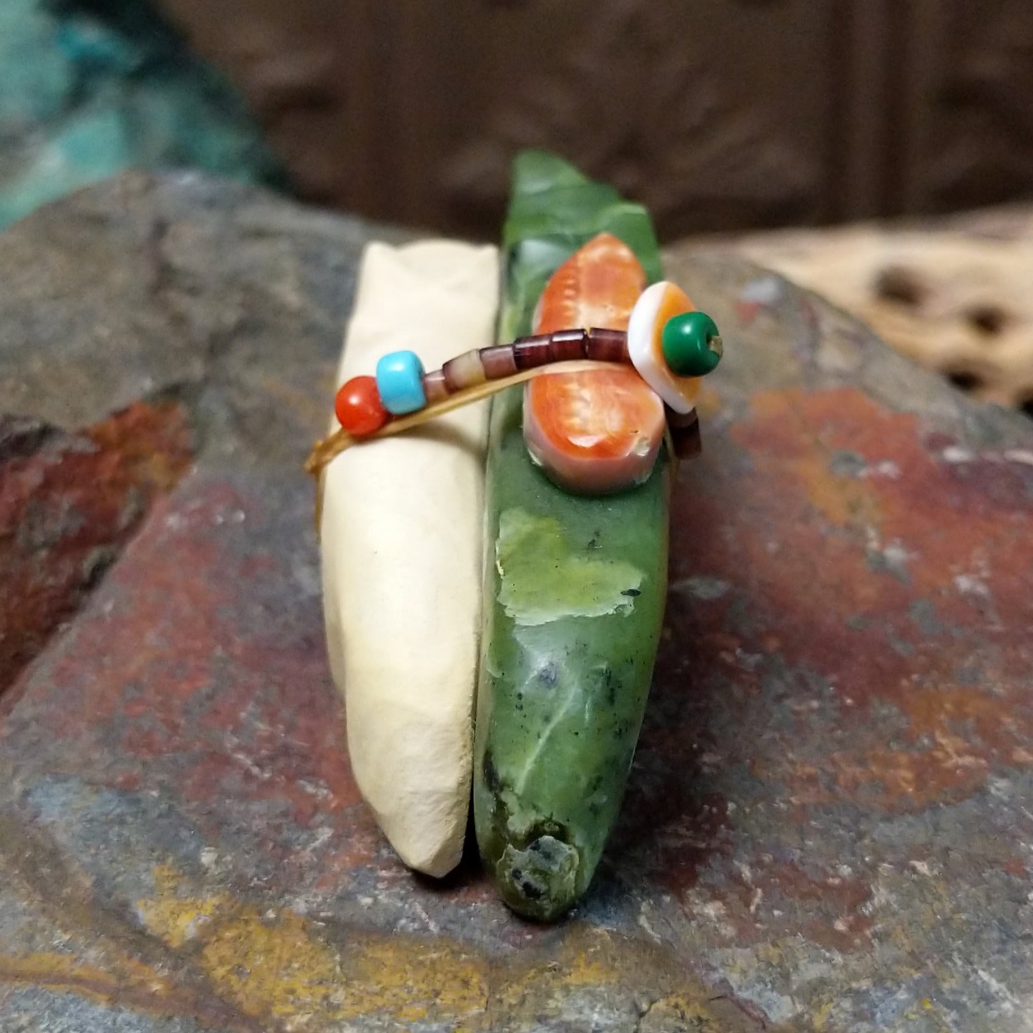 Zuni fox pair fetish carving by Jayne Quam featuring white and green stone foxes with a beaded medicine bundle.