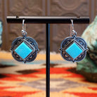 Sterling silver earrings with Kingman turquoise set in diamond-shaped bezels, framed by ornate stamped settings.