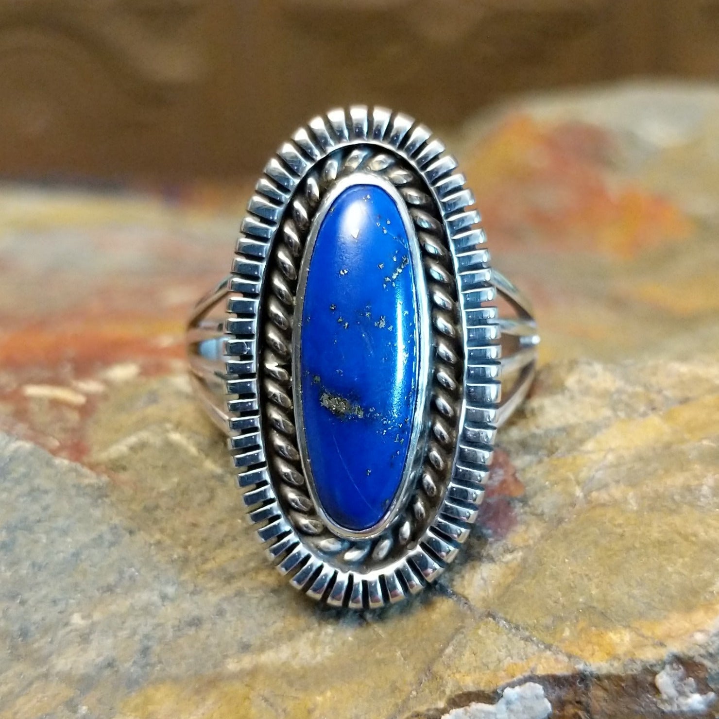 Sterling silver ring with oval lapis set in the bezel, framed by twisted rope and incised edges.